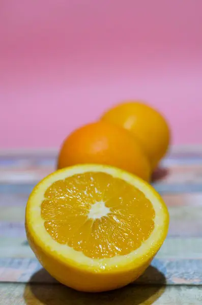 Pionowe Ujęcie Pokrojonej Pomarańczy Barwnym Stole — Zdjęcie stockowe