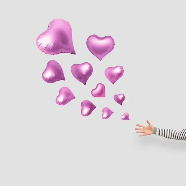 Розовые Шарики Форме Сердца Плавающие Белом Фоне Рукой Пытающейся Поймать — стоковое фото