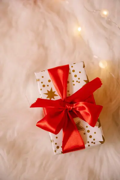 ライトで飾られた柔らかい布の上に赤い弓でクリスマスのギフトボックスのトップビュー — ストック写真