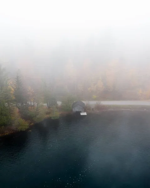 Вертикальный Снимок Дома Берегу Деревьями Покрытыми Туманом — стоковое фото