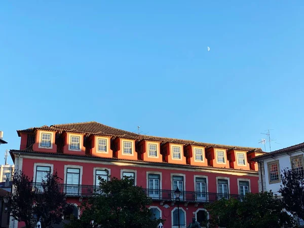 ポルトガルの青い空の下で太陽の光に照らされた多くの窓のある赤い建物のシーン — ストック写真