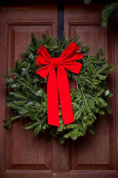 Вертикальный Снимок Рождественского Венка Двери Большим Красным Бантом — стоковое фото