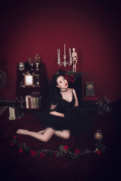 stock image A studio shot of an East Asian female model wearing a black mini dress with skulls in the background