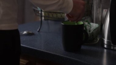 İçinde yeşil kaşık olan kahve bardağını karıştıran kişi....