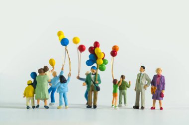 Beyaz arka planda izole edilmiş balonlu bir adam ve çocukların minyatür figürlerinin yakın çekimi.