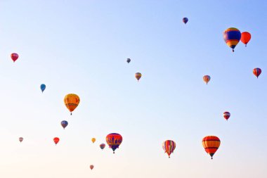 Albuquerque Uluslararası Balon Festivali sırasında güneşli, berrak gökyüzünde pek çok sıcak hava balonunun alçak açılı görüntüsü