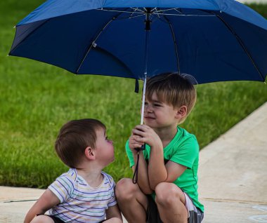 Dışarıda yağmurda şemsiyeyi tutan sevimli ağabey.