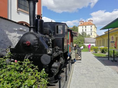 Litomerice tarihi şehrinde antik bir trenin yanında poz veren mutlu genç bir kadın.