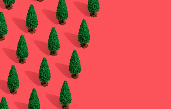 A minimal composition pattern background of green Christmas trees on pastel red surface-New Year concept