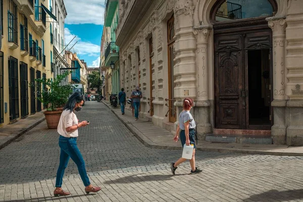 ハバナを歩いているキューバのラテン系の人々は 次の2人の女性の体に太陽が歩いて古い建物を復元し 人々は狭い通りから来ている — ストック写真