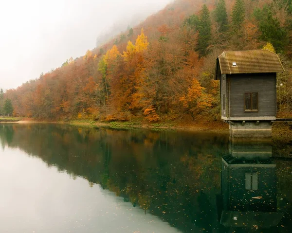 Malownicze Ujęcie Spokojnego Jeziora Odzwierciedlające Piękno Małego Domku Pomarańczowych Jesiennych — Zdjęcie stockowe
