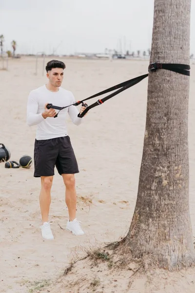 Młody Wysportowany Hiszpański Mężczyzna Ćwiczący Ciągnąć Ramiona Liną Plaży — Zdjęcie stockowe