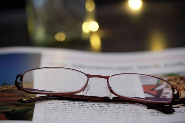 Olvasószemüveg Közelsége Egy Nyitott Könyvön Egy Asztalon — Stock Fotó