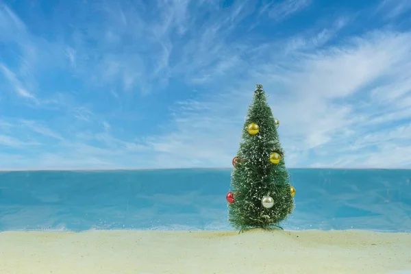 Ein Miniatur Weihnachtsbaum Mit Kugeln Vor Einem Falschen Strandhintergrund — Stockfoto