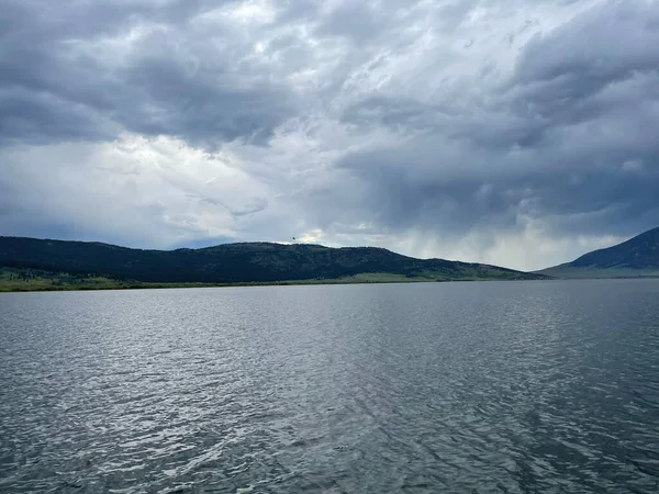 Chmurne Ciemne Niebo Nad Jeziorem Zielonym Tle Wzgórza — Zdjęcie stockowe