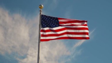 Bulutlu mavi gökyüzüne doğru dalgalanan ABD bayrağının alçak açılı görüntüsü.