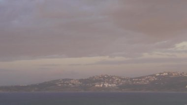 Gün batımında suyla çevrili dağ manzarası.