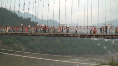 Rishikesh, Hindistan - 18 Ekim 2022 - Ram Jhula Köprüsü 'nde yürüyen insanlar