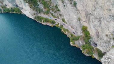 Trentino, İtalya 'da bir gölün kenarındaki tünele giden bir yolun drone görüntüsü.
