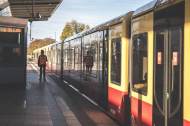 Berlin 'de güneşli bir günde tren istasyonunda duran bir metro işçisinin görüntüsü.