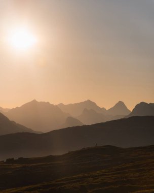 İtalyan Dolomitleri ve mavi gökyüzündeki batan güneşin dikey görüntüsü.