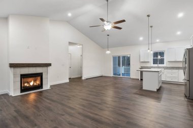 Beyaz duvarları, parke zemini, asılı lambaları ve şöminesi olan bir evin içi.