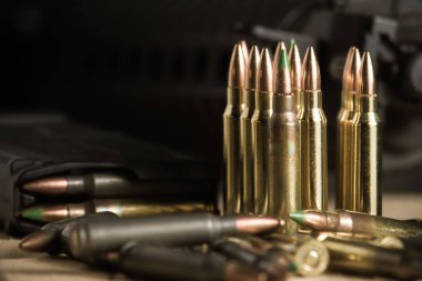 Cephaneyle dolu bir AR-15 şarjörünün yanında ya da yanında duran 223 tüfek mermisi var.