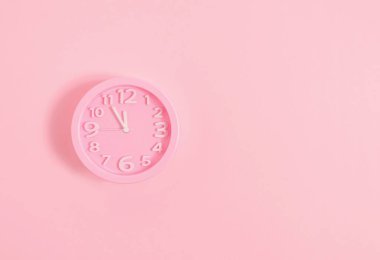 Pembe boyalı duvar Noel arifesinde ya da yeni yıl konseptinde pastel pembe bir alarm saati.