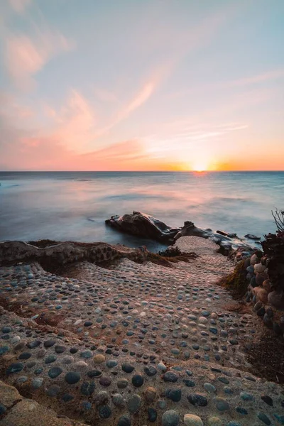 Вертикальный Снимок Каменной Дорожки Ведущей Голубому Океану Золотым Небом Закате — стоковое фото