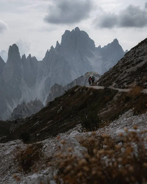 Вертикальный Снимок Двух Человек Путешествующих Итальянским Доломитам Облачным Небом — стоковое фото