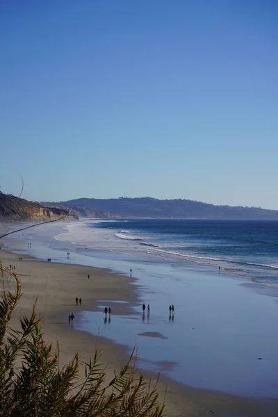 在蓝天的映衬下 人们在海滩上散步的垂直镜头 — 图库照片