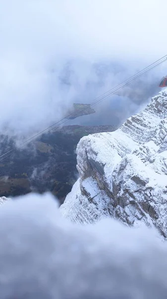 Красивый Вертикальный Снимок Густого Тумана Покрывающего Скалистые Горы Покрытые Снегом — стоковое фото