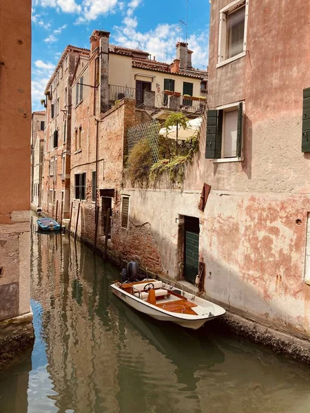 イタリアのヴェネツィアの歴史的建造物を通って運河に浮かぶボートの垂直ショット — ストック写真