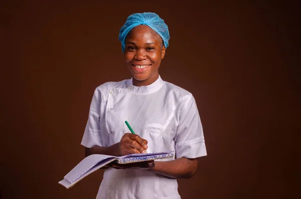 Close Uma Bela Enfermeira Sorrindo Tomando Notas Sobre Fundo Marrom — Fotografia de Stock