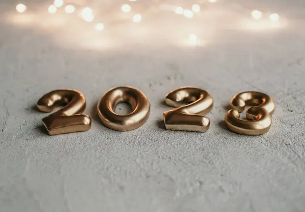 stock image Close-up photo of golden number 2023 on concrete surface with bokeh lights