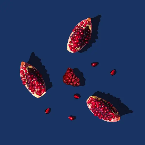 stock image A top view of fresh slices of pomegranate on a blue background.