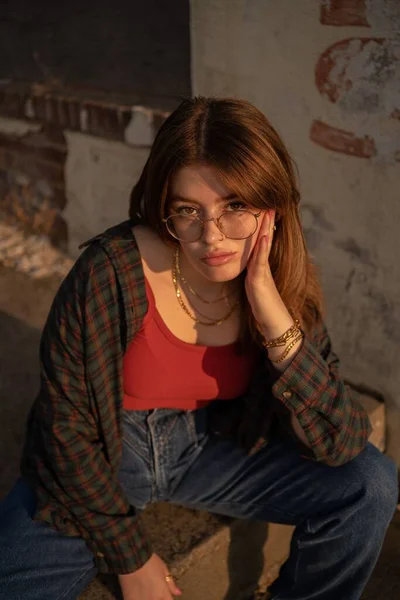 歩道に座っている眼鏡をかけた魅力的な女性の垂直閉鎖背景 — ストック写真