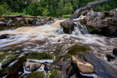 Kayaların üzerinden akan bir şelalesi olan güzel bir manzara.