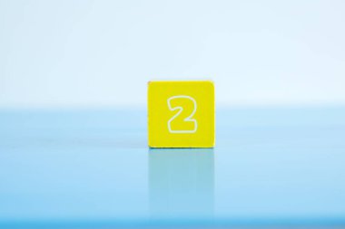 Mavi arkaplanda iki numara olan küpün yakın plan fotoğrafı.