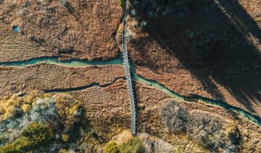 Slovenya 'daki Zelenci ağ rezervindeki çayır boyunca akan derenin üzerindeki köprüden doğrudan hava manzarası