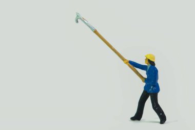 Beyaz arka planda elinde sopayla duran minyatür bir itfaiyeci figürü.