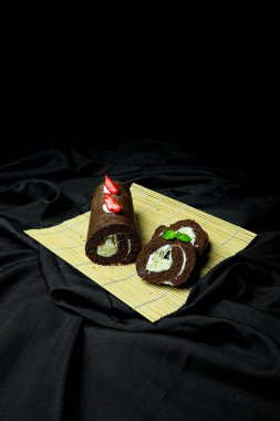 Çukulatalı İsviçre böreğinin dikey yakın çekimi, saman tabaktaki böğürtlenler, koyu arkaplan