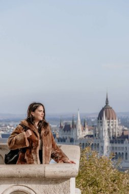 Arka planda Budapeşte şehri olan bir kızın taş bir balkonda dikey görüntüsü.