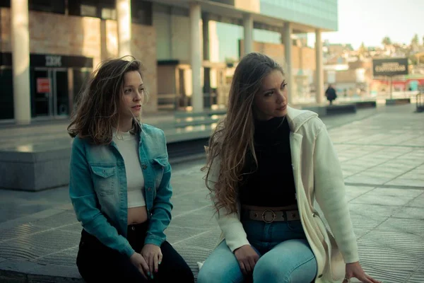 都会の屋外で一緒に座っている若いスタイリッシュな女性の友人のペア — ストック写真