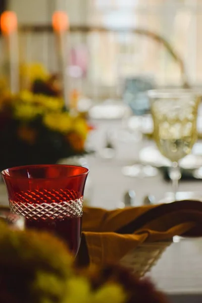 背景がぼやけているテーブルの上に赤いガラスカップの垂直ショット — ストック写真