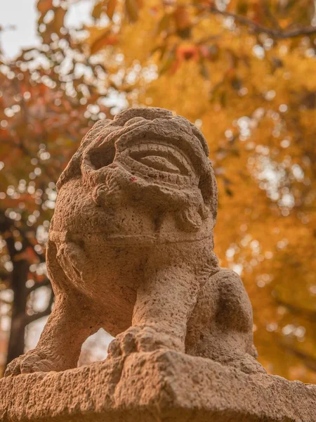 Ein Vertikaler Selektiver Fokus Einer Antiken Löwenstatue Mit Herbstbäumen Hintergrund — Stockfoto