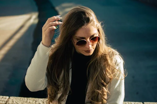 太陽の光の下屋外に座ってサングラスを持つ若い女性の肖像画 — ストック写真