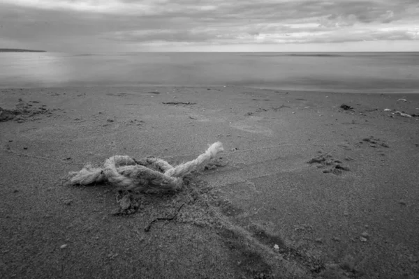 在阴沉沉的一天 海滩上一条灰色的绳子在多云的天空下被大海环抱着 — 图库照片