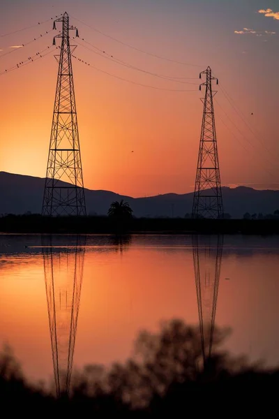 Vertikální Záběr Oranžového Západu Slunce Nad Jezerem Něm Odrážel Elektrických — Stock fotografie