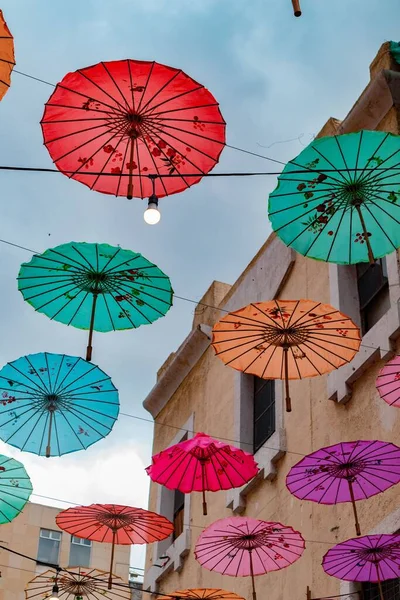 Een Verticaal Shot Van Kleurrijke Paraplu Hangend Lucht Tussen Gebouwen — Stockfoto